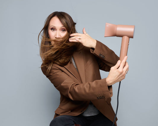 Anna Nowak-Ibisz z rozwianymi włosami na twarzy i suszarką SkinVibe Aurea Family x Plasma w kolorze Mocha Mousse
